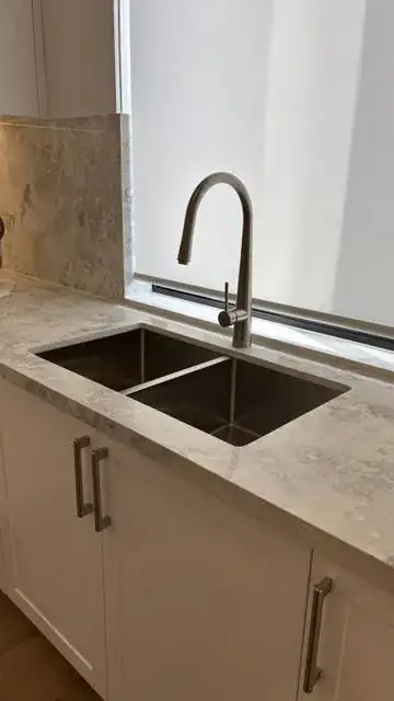 New kitchen sink and mixer tap installed in a stone benchtop